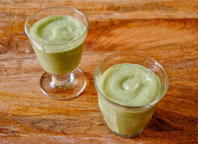 green smoothie in two glasses on wooden surface