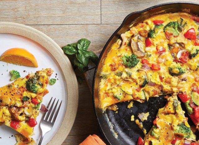 loaded vegetable frittata in a cast iron pan with a plate on a plate and fork