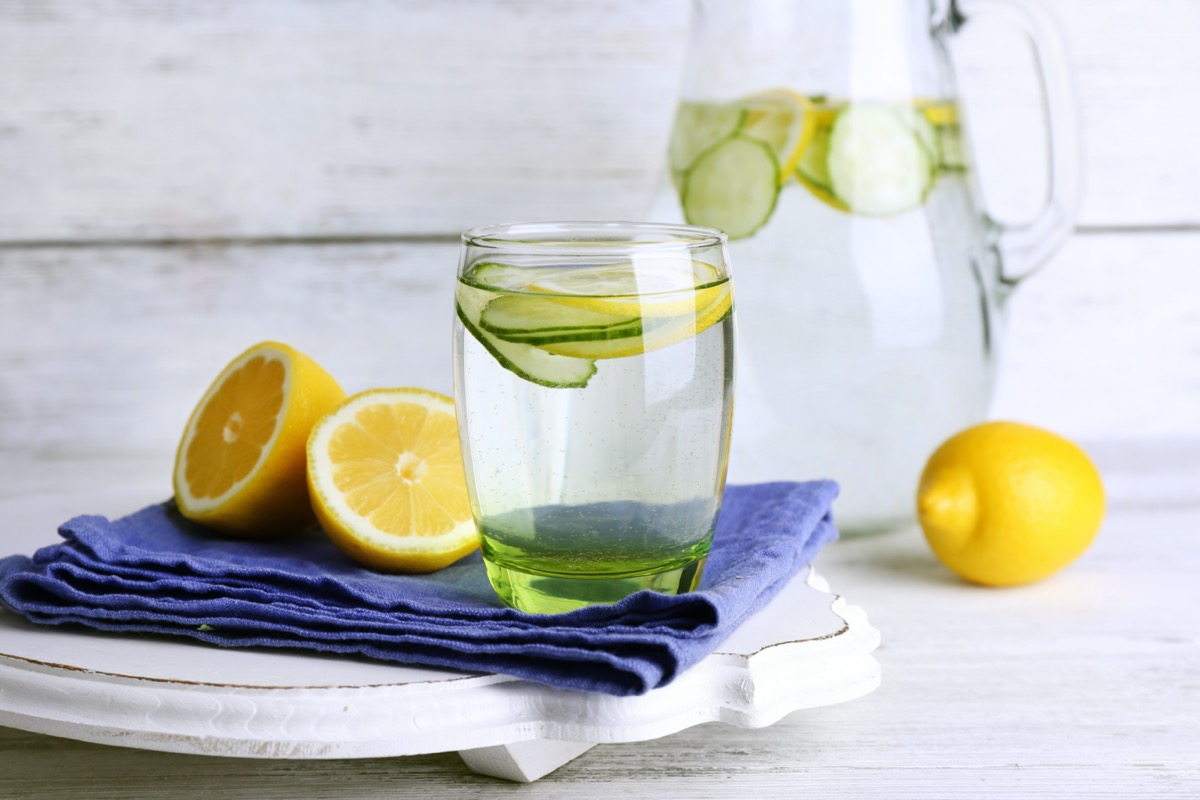 fresh water with lemon and cucumber in glass on wooden background