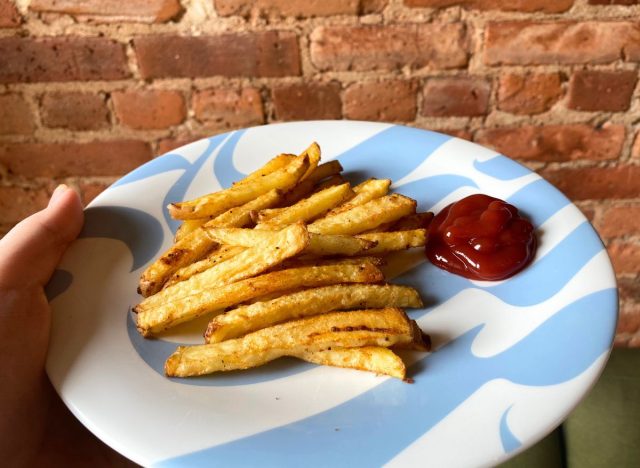 hand holding a plate of french fries