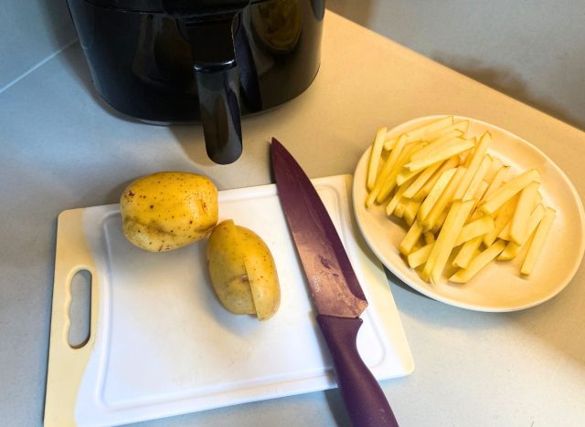 potatoes and a knife next to a plate of sliced ​​potatoes