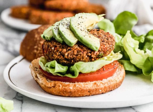 veggie burger on a bun with avocado slices, lettuce and tomato