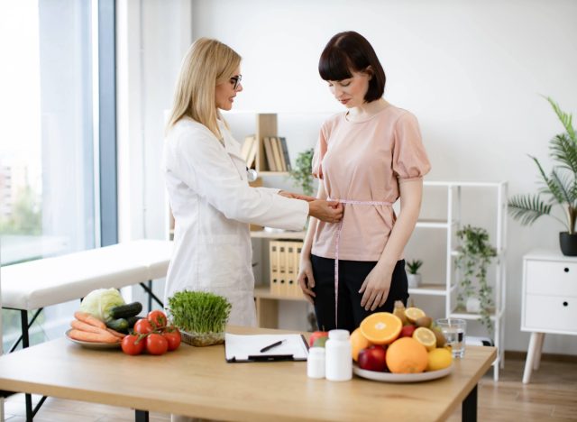 doctor or nutritionist measuring a patient's waist