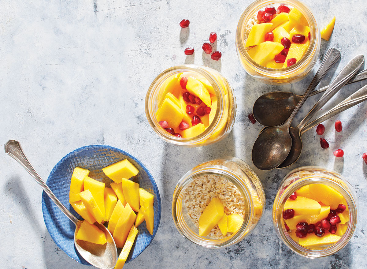 mango ginger overnight oats cans with spoons and pomegranate seeds