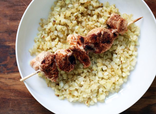 as many as 30 chicken kababs over celeriac rice on a plate