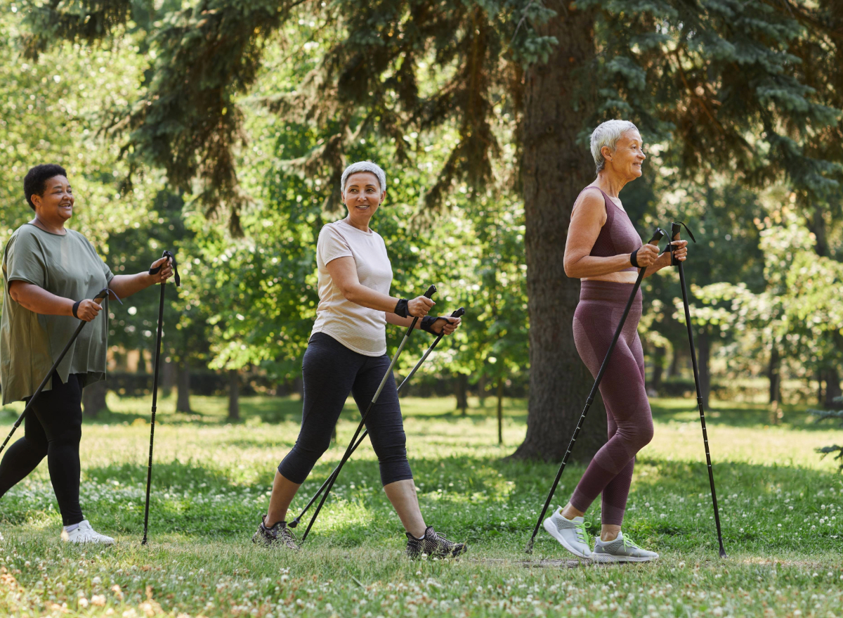 mature women with walking sticks walking through nature for exercise