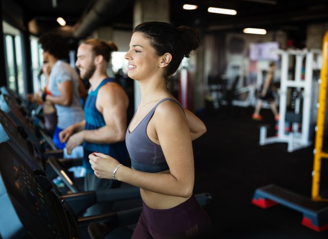 woman doing cardio on treadmill in gym with friends