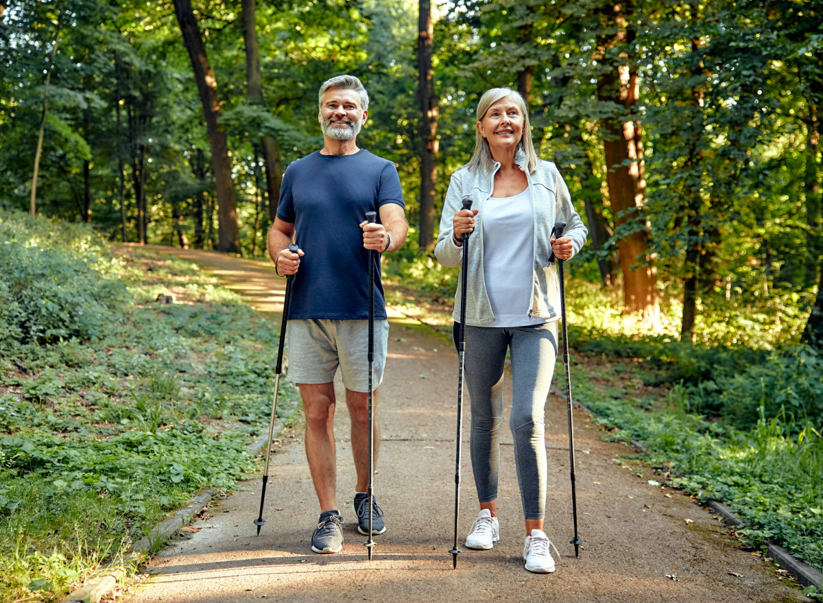 happy mature couple doing pole walking on hiking trail