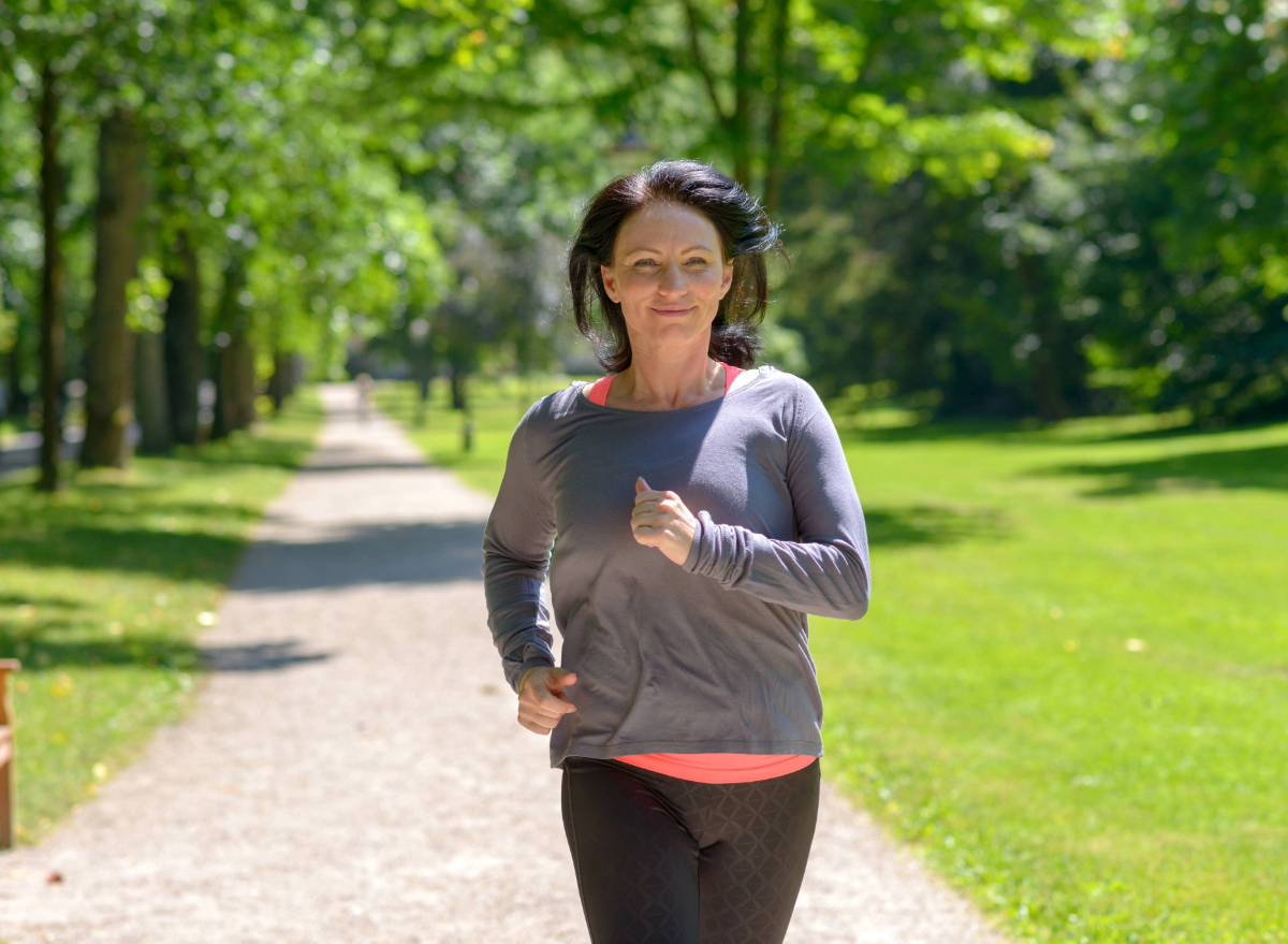 middle aged woman running outdoors, the concept of how often to do cardio to lose belly fat