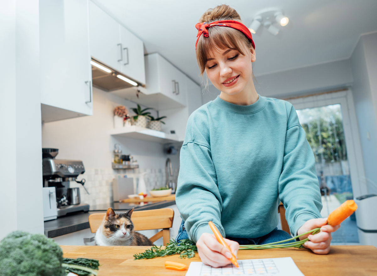 woman writes meal preparation schedule in calendar