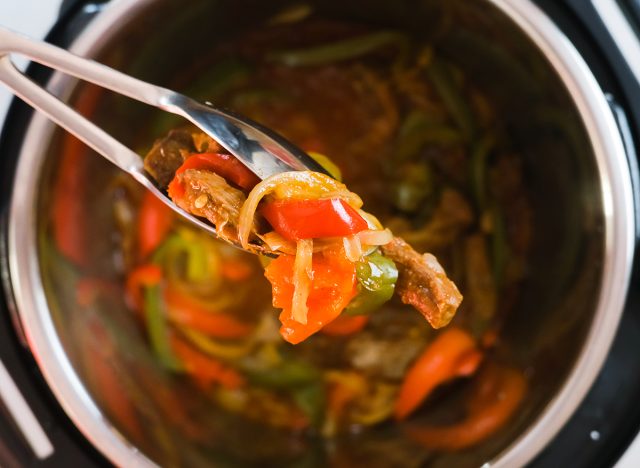 holding steak fajita filling with tongs from an instant pot