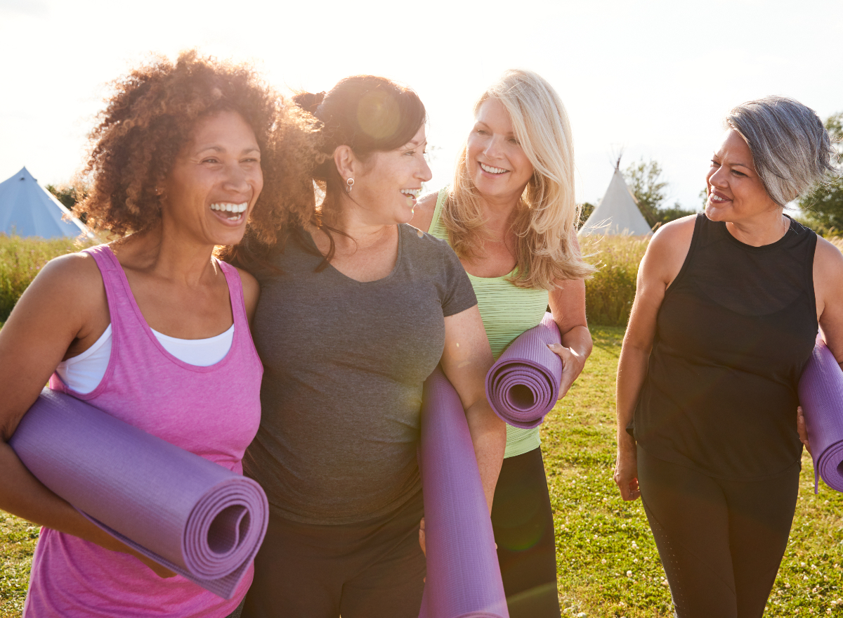 friends holding yoga mats going to outdoor yoga class