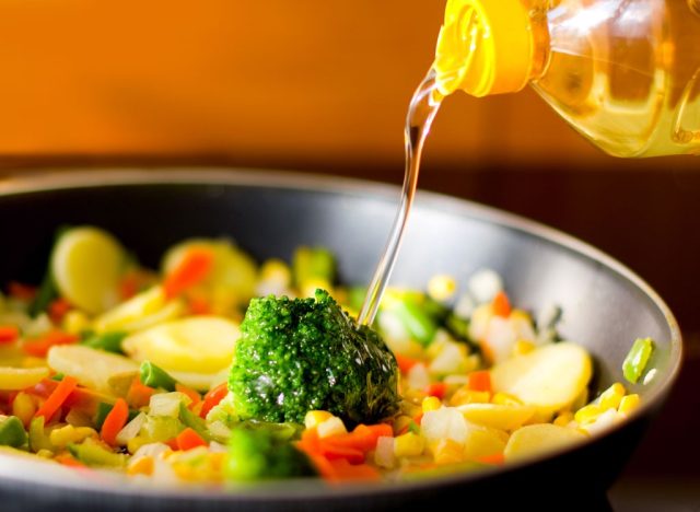 pour vegetable oil on vegetables in a frying pan