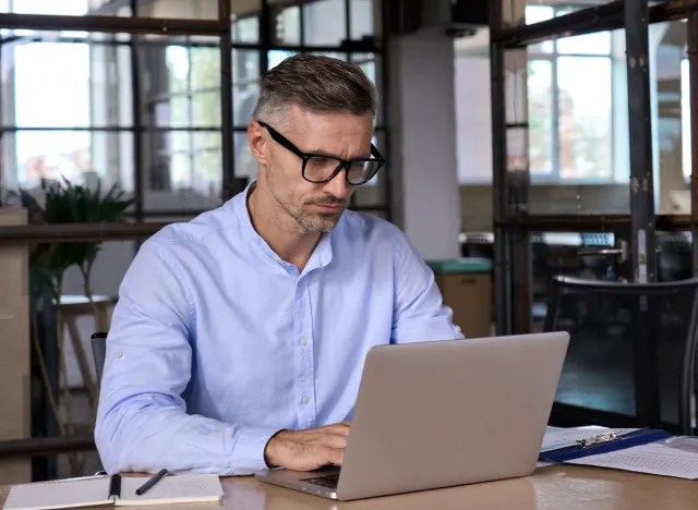 man typing on laptop at table, desk setting