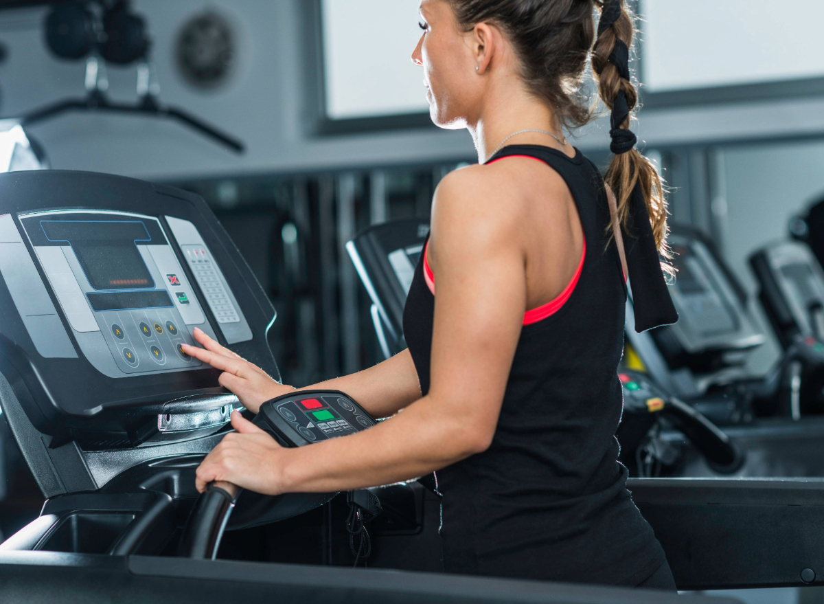 woman adjusting incline of treadmill at gym