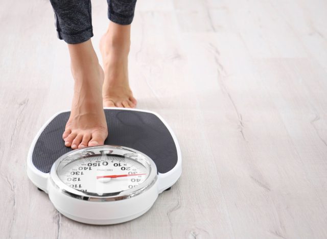 woman stepping on the scale, concept of how much weight to safely lose in a month