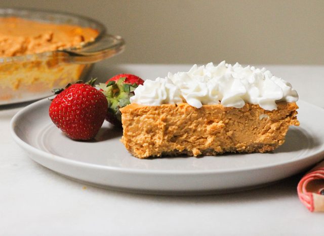 slice of healthy pumpkin cheesecake with whipped cream and strawberries