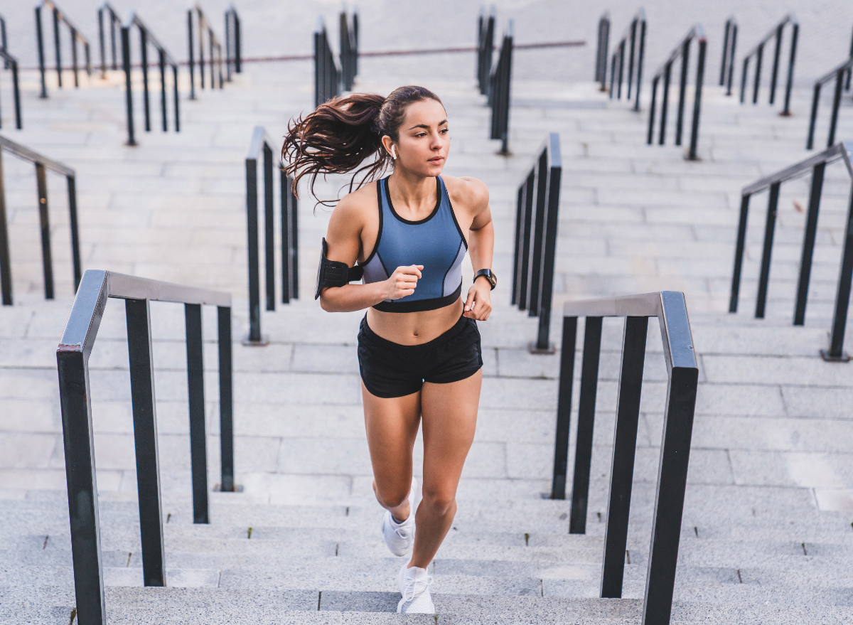 woman running up stairs, concept of tips to avoid belly fat