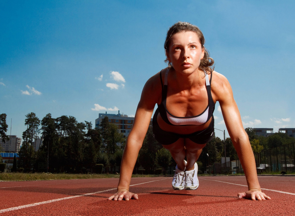 fit woman doing push-ups or planks on track, concept of body weight training for flabby arms