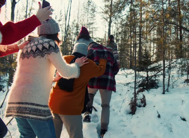 family in line taking a snowy walk on christmas in sweaters and hats in the forest