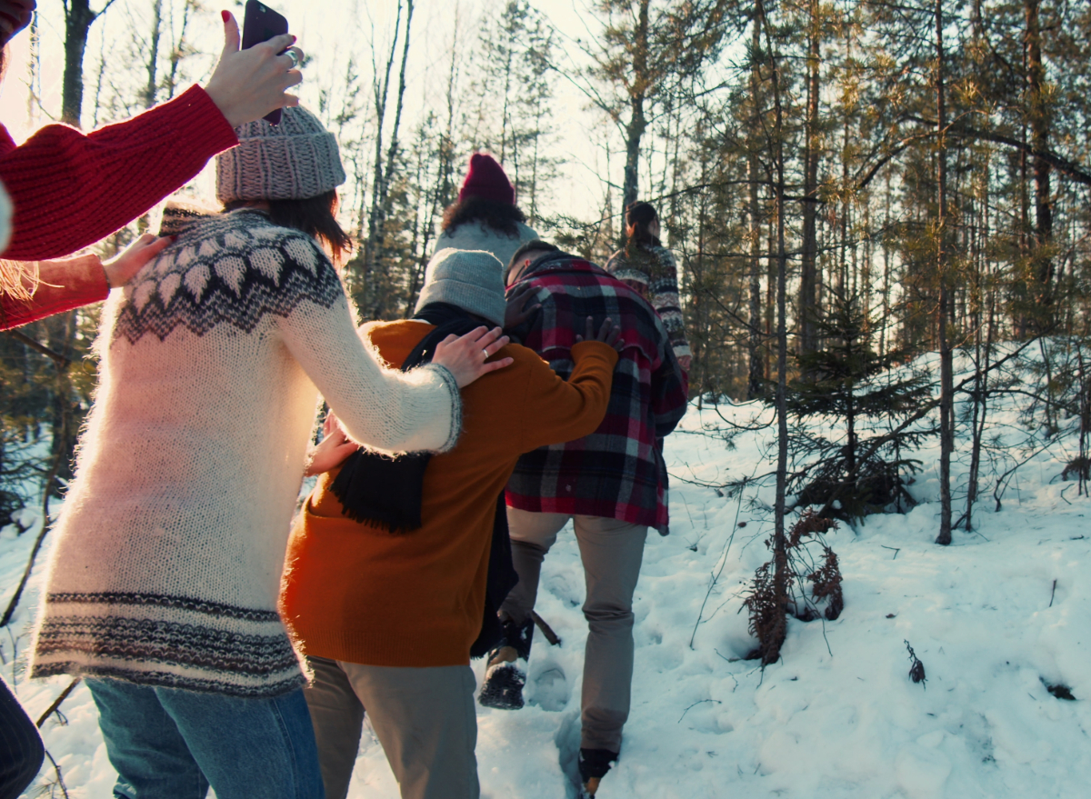 family in line taking a snowy walk on christmas in sweaters and hats in the forest