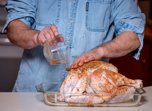 adding a dry brine seasoning rub to a raw turkey