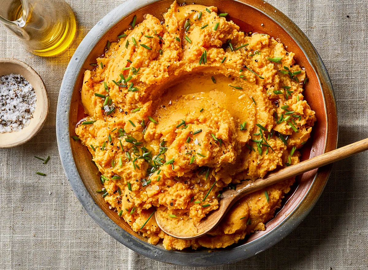 pumpkin mashed potatoes in a large bowl with chives, oil and salt.