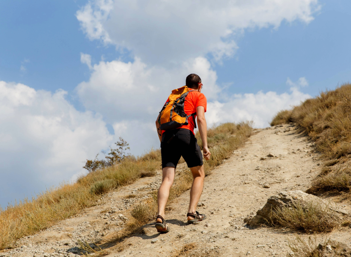 man rushes uphill on hiking trail on sunny day