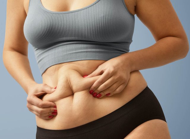 5 effective strength training moves to reduce your "apron belly" 31 woman holding belly fat