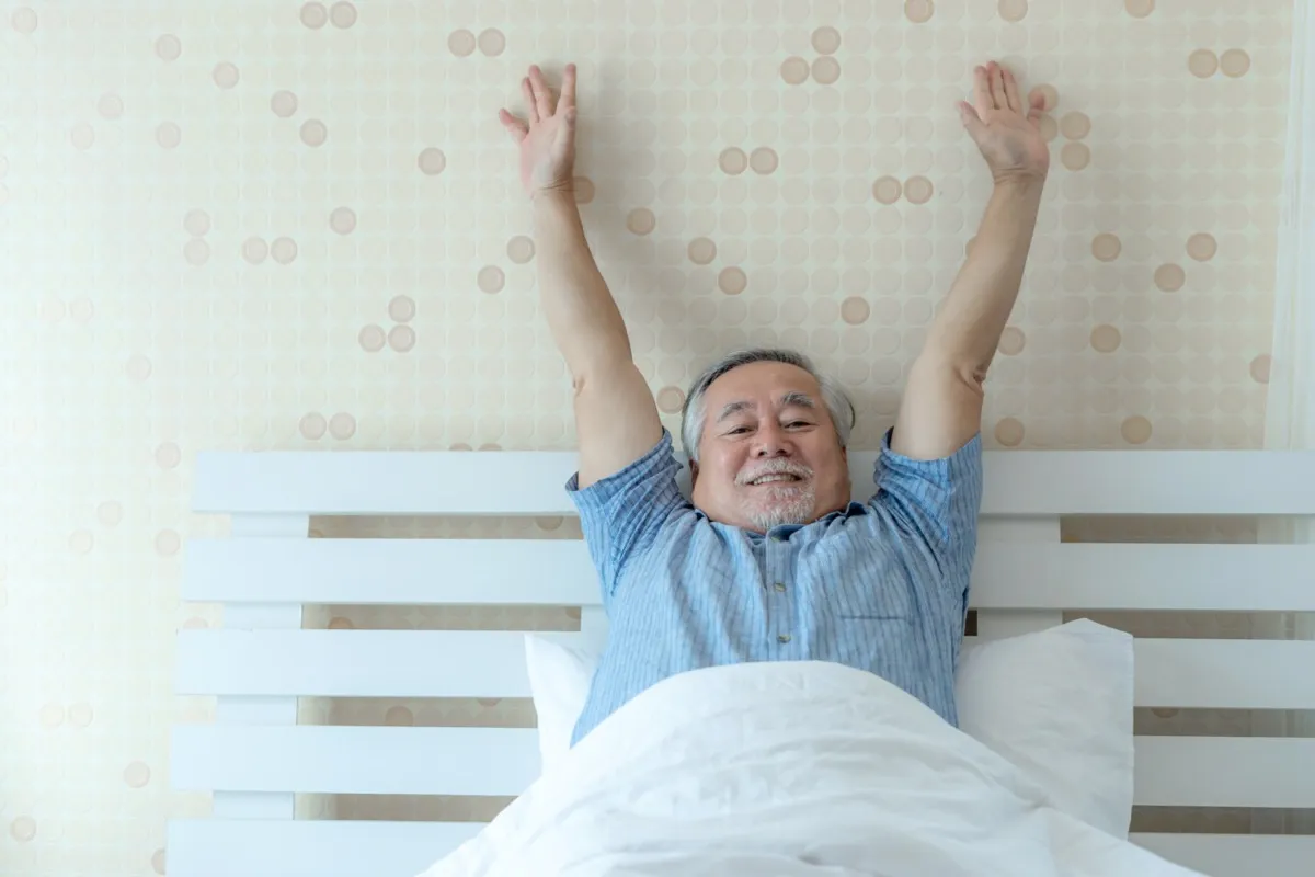 happy senior man good health wakes up in the morning with joy in his bedroom