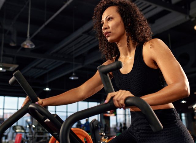 woman riding an air bike at the gym, the concept of the best abdominal exercises to do at the gym