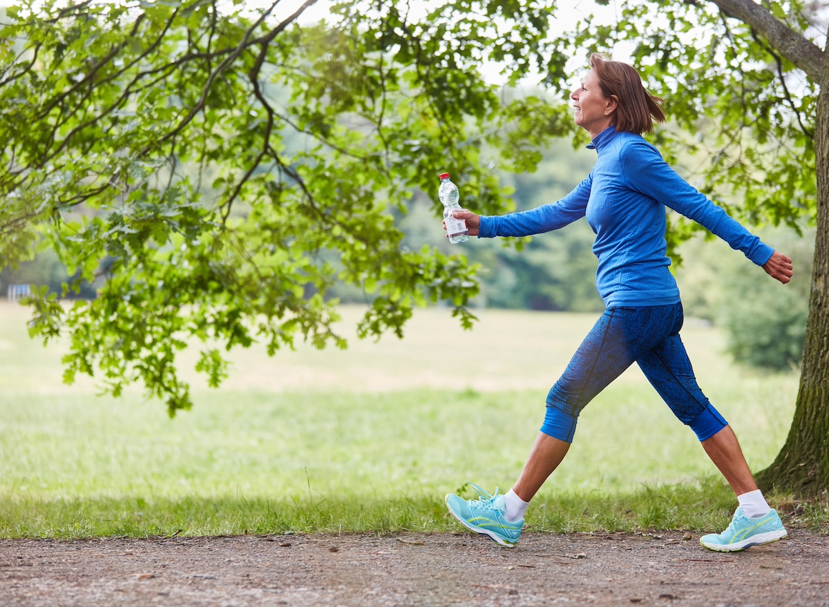 mature woman on brisk walk on trails, concept of low impact exercises to melt belly fat