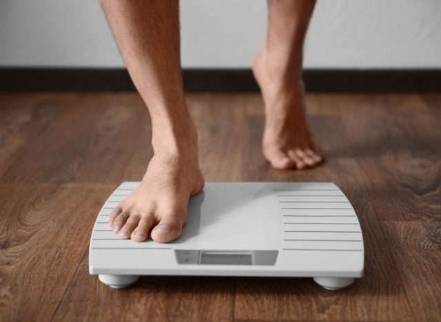 close-up man stepping onto the scale