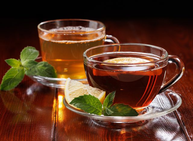 warm green tea with mint and black tea with lemon and mint in glass cups. side view. selective focus.