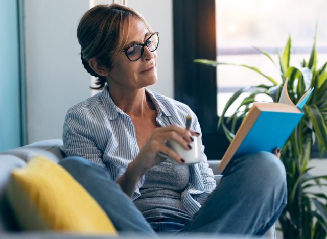 woman sitting comfortably on a couch reading a book