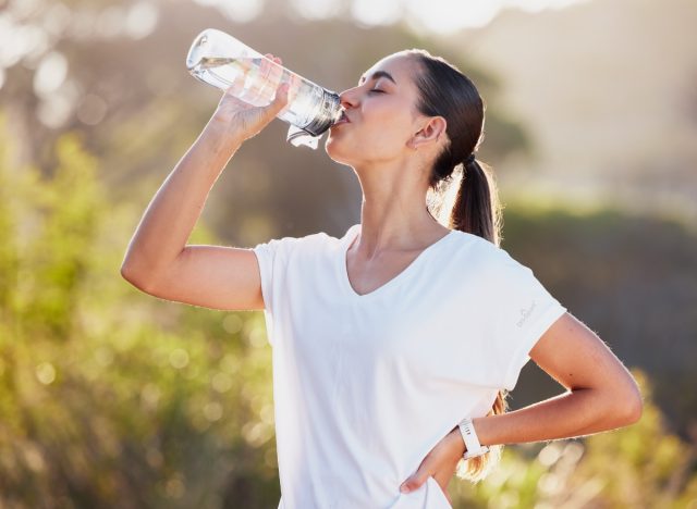 a happy woman with a water bottle post-exercise