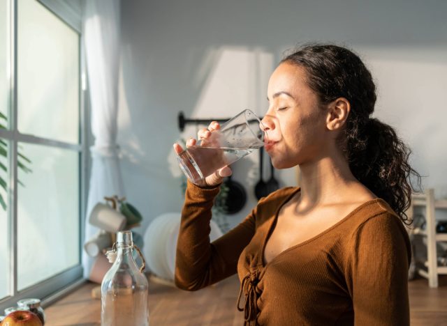 woman enjoying water in a bright kitchen