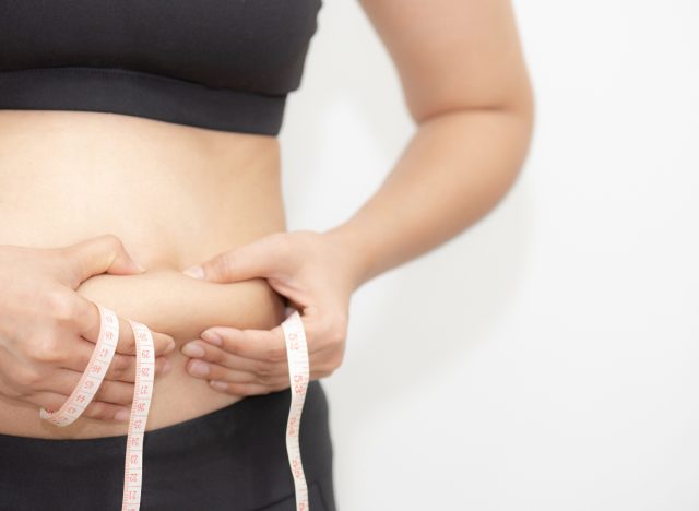 a woman expressing concern over belly fat, encapsulating the struggle many face in a comprehensive training plan.