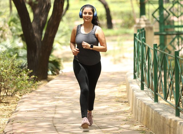 cheerful woman jogging and walking in the garden ramp with headphones