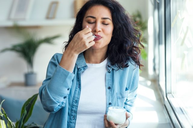 woman smiling while eating yogurt