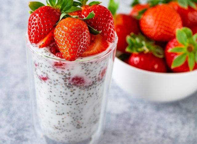 close -up chia pudding with berries, straws, raspberries on the rustic background