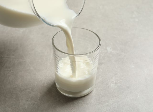 Pour milk into glass on gray table